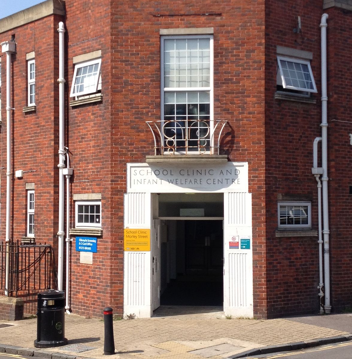 Red-brick corner building with a stone doorway reading School Clinic and Infant Welfare Centre